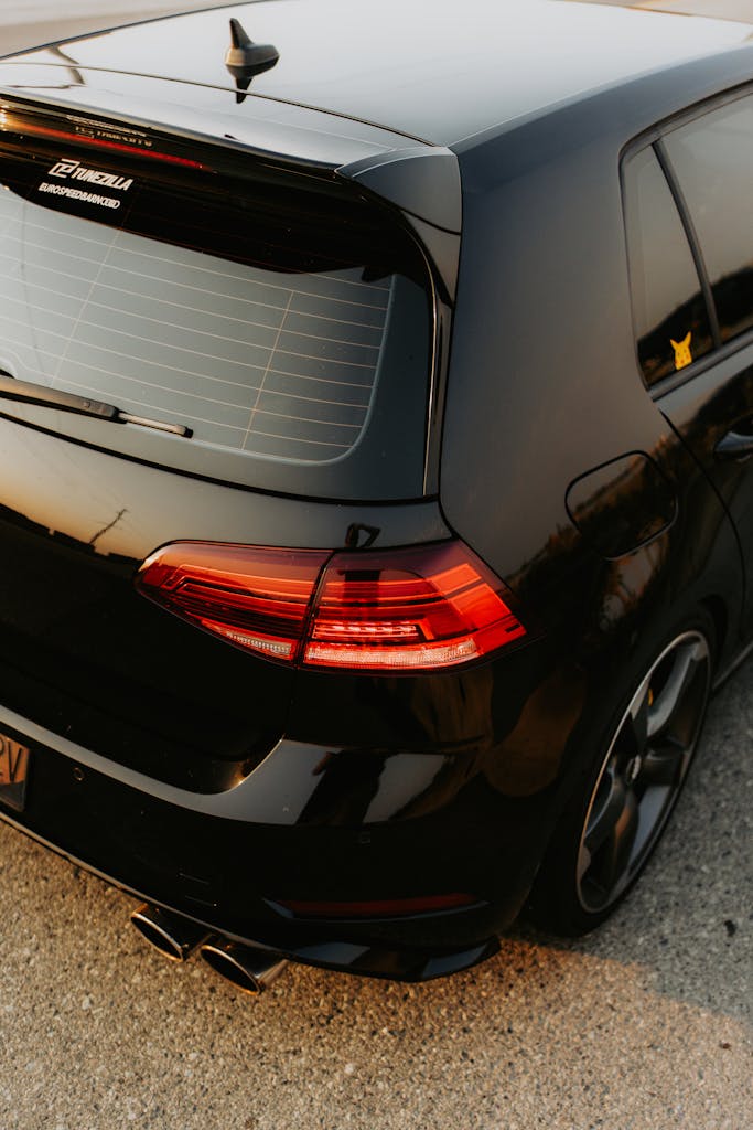 A close-up rear view of a black hatchback car with modern design elements, captured at sunset.