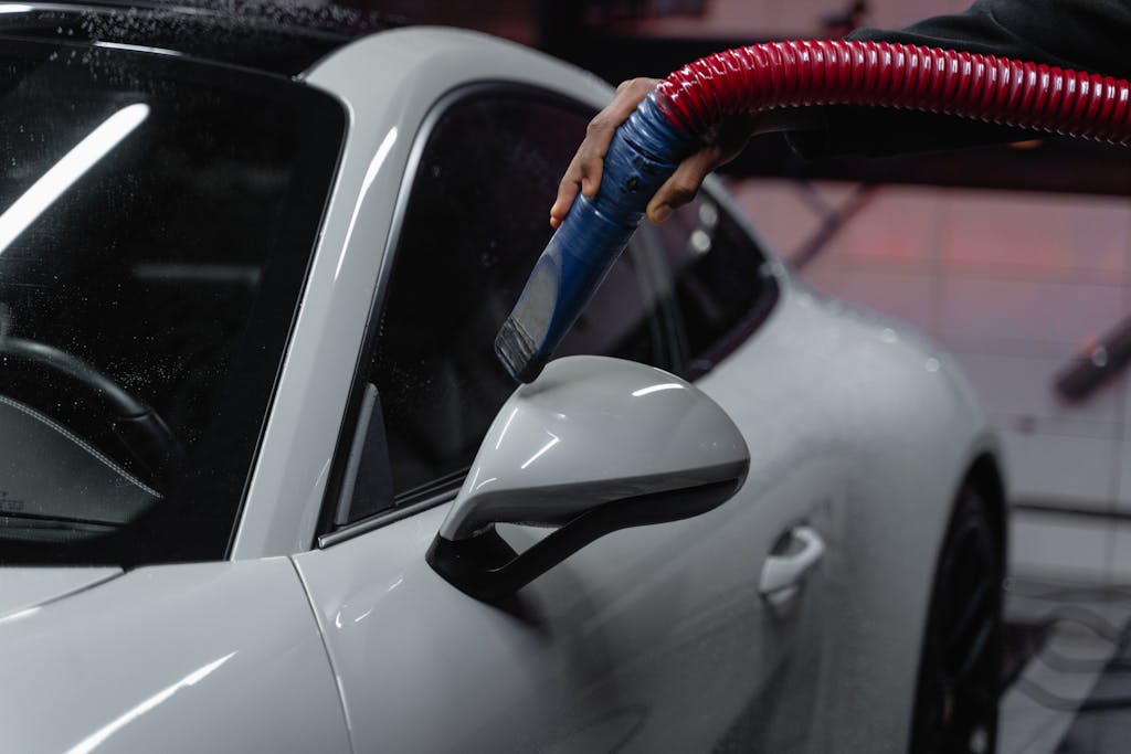 A white sports car is meticulously vacuumed indoors for a flawless shine and maintenance.