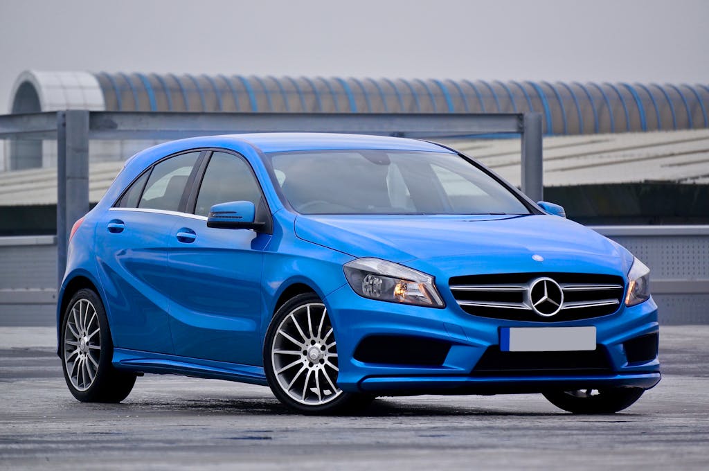 Elegant blue Mercedes-Benz hatchback parked outdoors with a modern architectural backdrop.