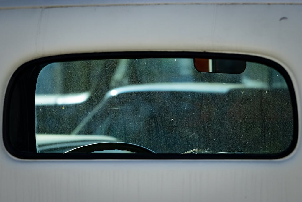 Gritty reflection of city streets seen through a car's rear window, capturing urban life.