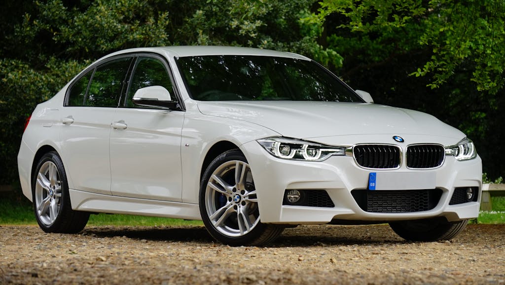 White BMW car parked on gravel path surrounded by greenery, showcasing luxury design.